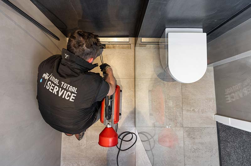 Monteur van Riool Totaal Service ontstopt een toilet met de ontstoppingsmachine