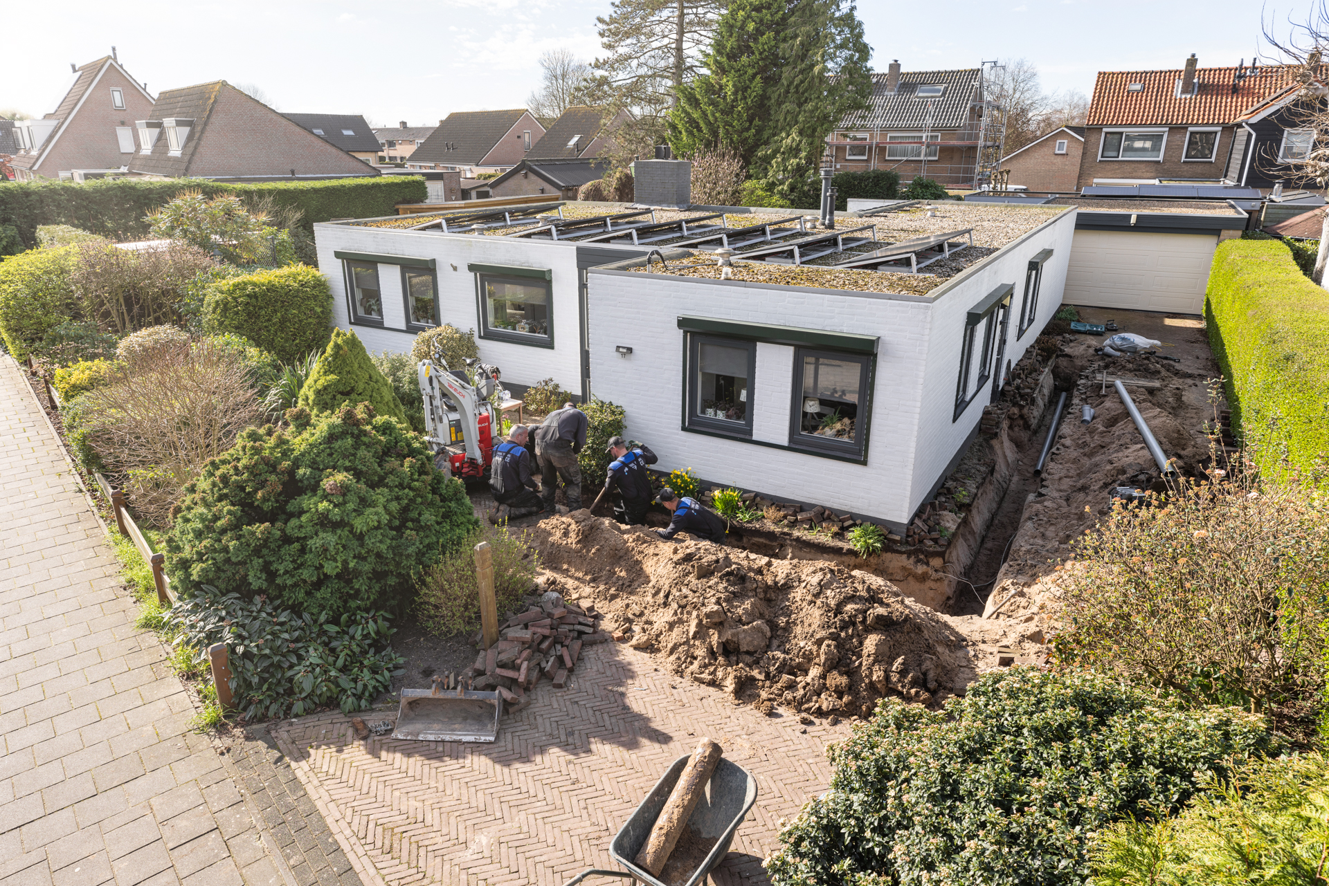 Luchtfoto van een woning waar het team in de tuin aan het riool werkt